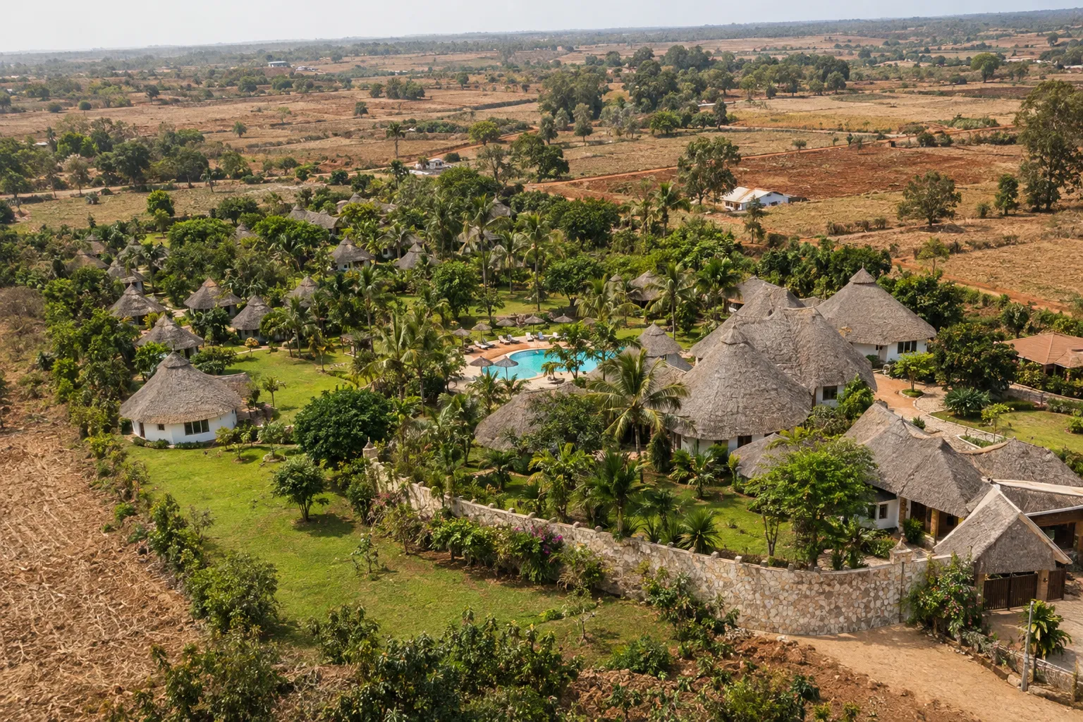 Lodge mit Strohdächern und Pool zwischen Feldern bei Karatu, Luftaufnahme